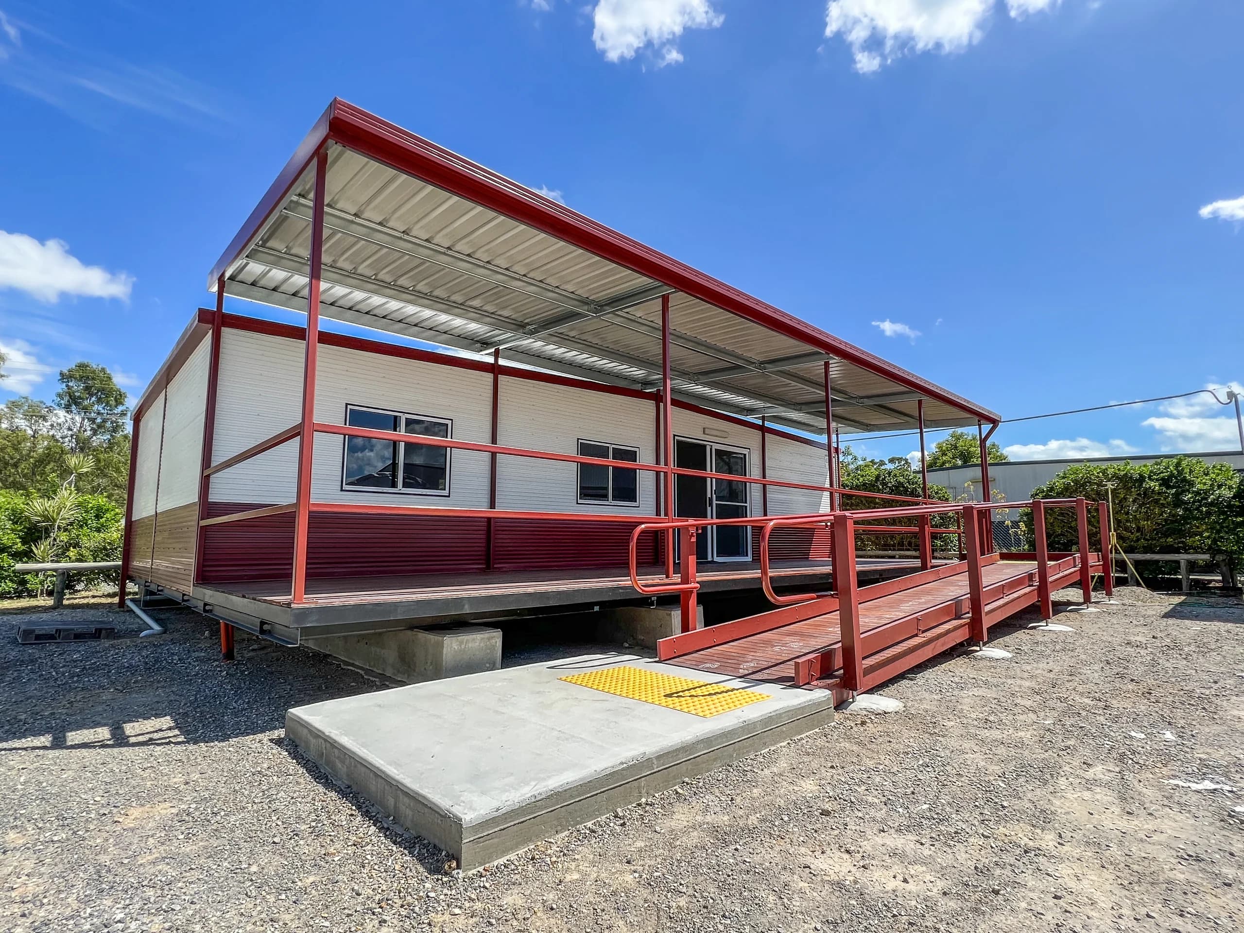 Building with a red-framed access ramp, canopy and new concrete landing